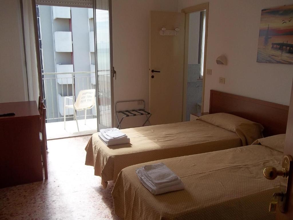 une chambre d'hôtel avec deux lits et un balcon dans l'établissement Hotel Italia, à Senigallia