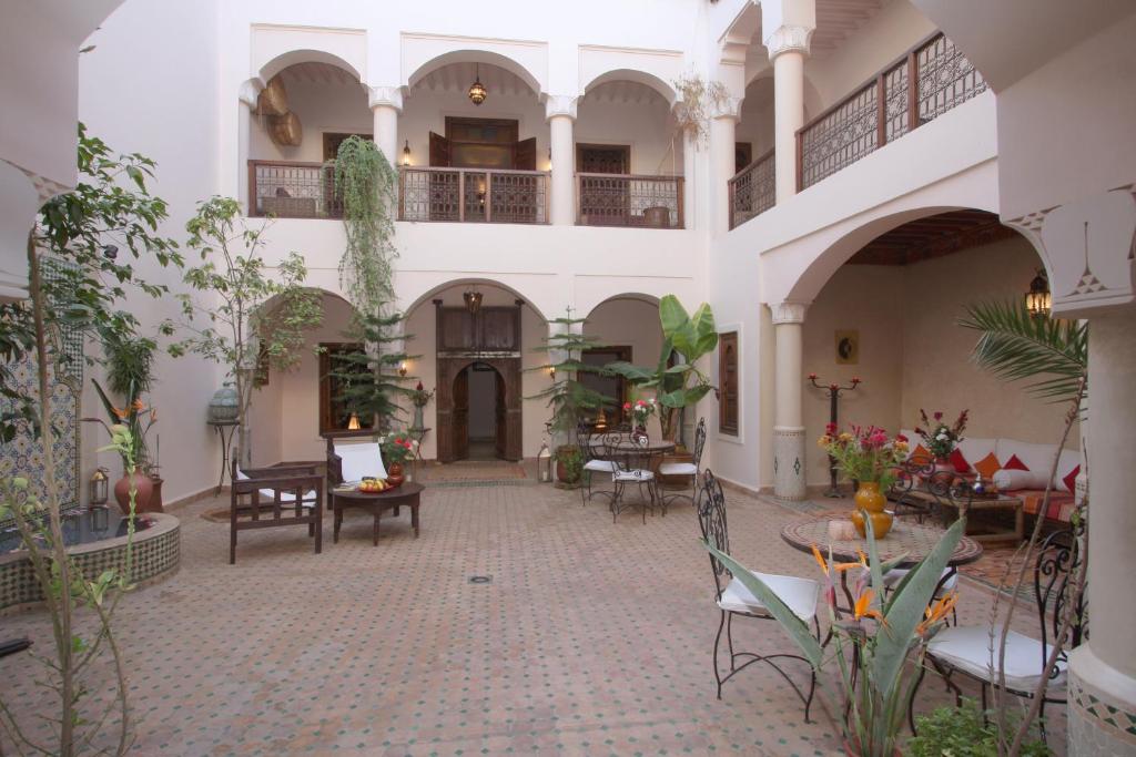une cour avec des tables et des chaises dans un bâtiment dans l'établissement Riad Cannelle, à Marrakech