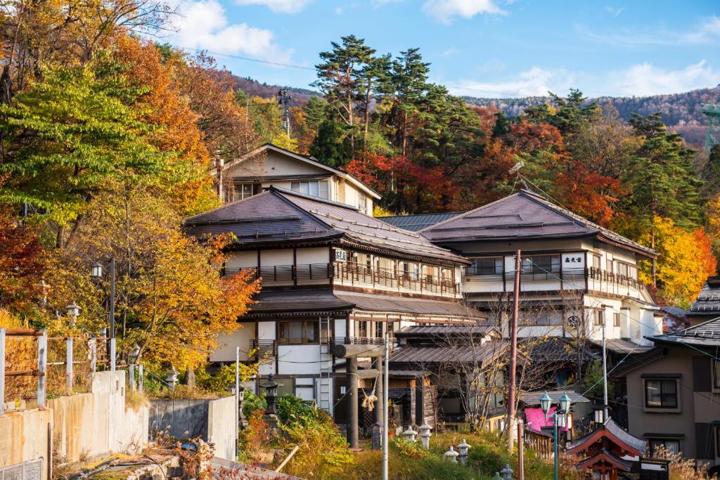 une grande maison sur le côté d'une montagne dans l'établissement Takamiya Ryokan Miyamaso, à Zao Onsen
