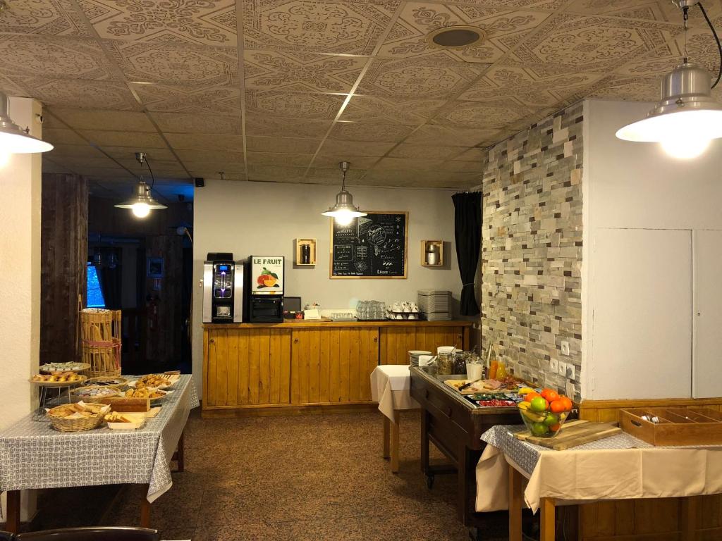une cuisine avec deux tables et un comptoir avec de la nourriture dans l'établissement Hôtel Les Trappeurs, aux Orres