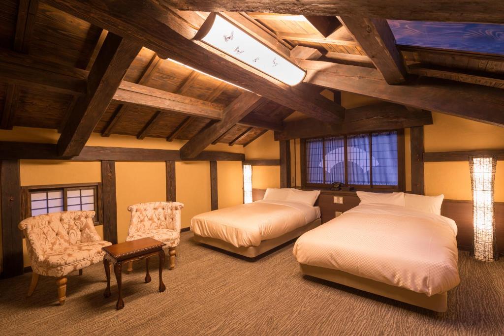 une chambre avec deux lits dans une pièce avec des plafonds en bois dans l'établissement Yamabiko Ryokan, à Minamioguni