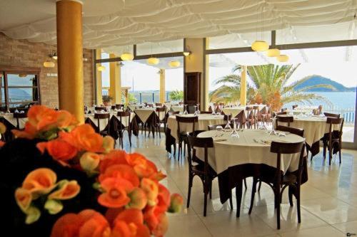 un restaurant avec des tables blanches, des chaises et des fleurs dans l'établissement Residence Sole, à Albenga