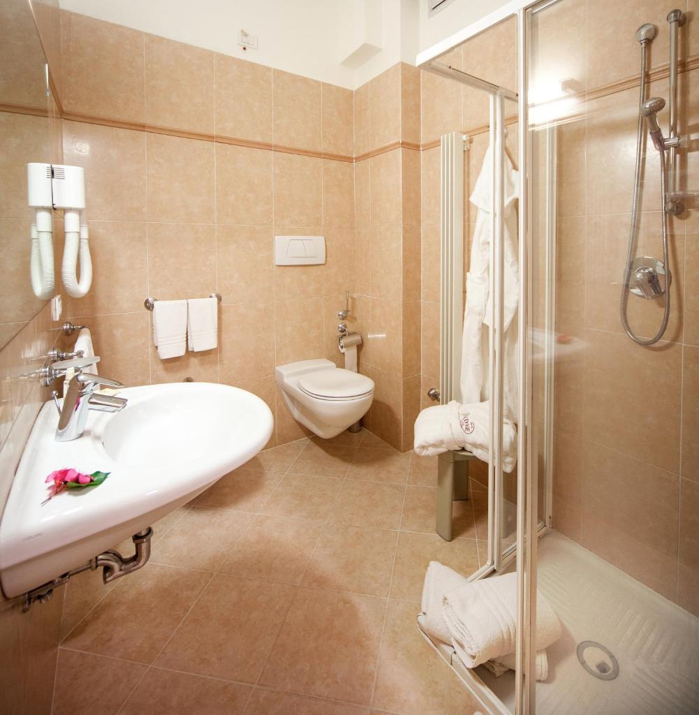 une salle de bain avec un lavabo, des toilettes et une douche dans l'établissement Hotel Doge, à Milano Marittima