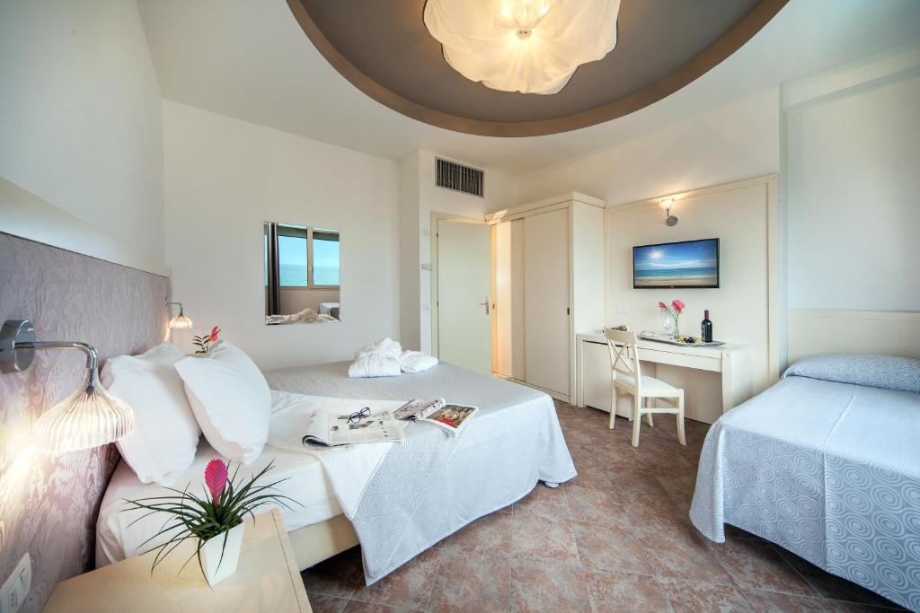 une chambre d'hôtel avec deux lits et un bureau dans l'établissement Hotel Doge, à Milano Marittima