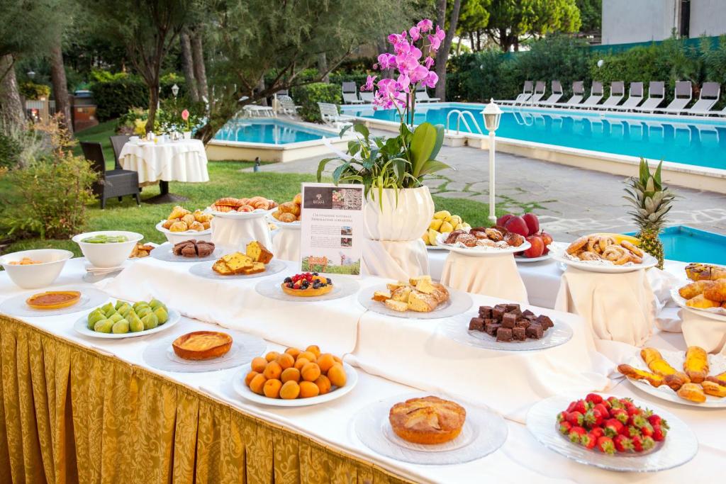 - un buffet de fruits et de viennoiseries sur une table au bord de la piscine dans l'établissement Hotel Doge, à Milano Marittima