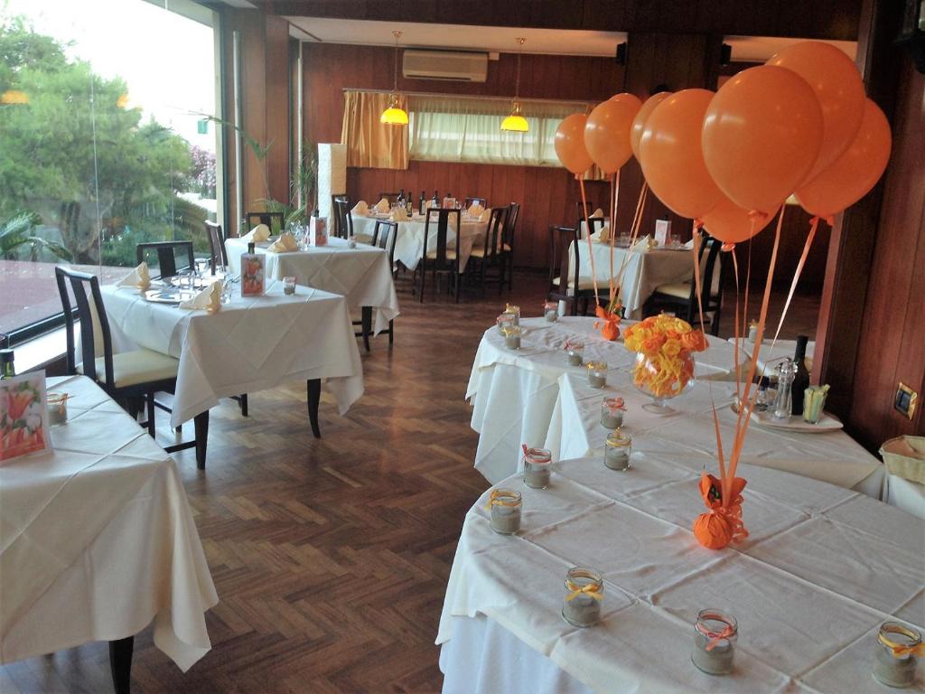 - un restaurant avec des tables blanches et des ballons orange dans l'établissement Hotel La Perla Preziosa, à Grottammare
