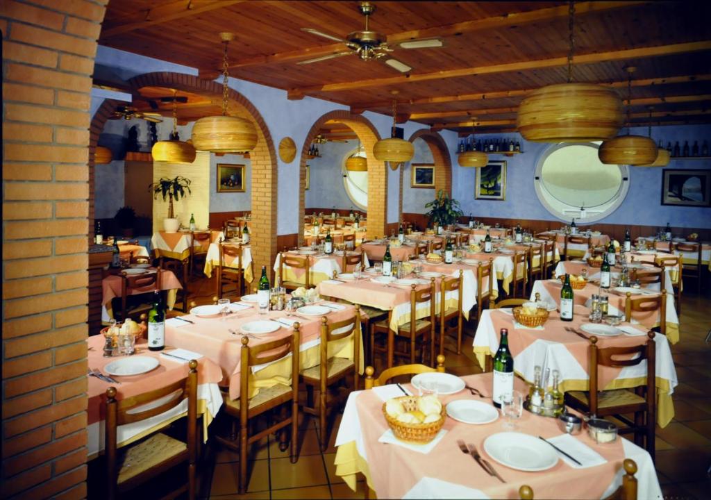 une salle à manger avec des tables et des chaises avec des nappes blanches dans l'établissement Hotel Cesari, à Rimini