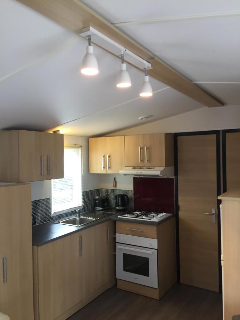 une cuisine avec des armoires en bois et un four à plaques de cuisson dans l'établissement Mobil home 6 pers, 3 ch, Kerlann**** Bretagne Sud, à Pont-Aven