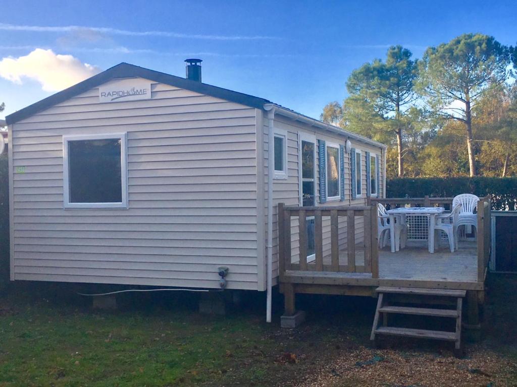 une maison blanche dotée d'une terrasse avec une table et des chaises dans l'établissement Mobil home 6 pers, 3 ch, Kerlann**** Bretagne Sud, à Pont-Aven