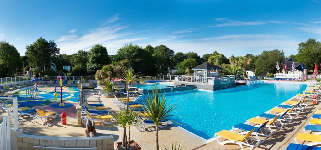 - une grande piscine avec des chaises et des parasols dans un complexe dans l'établissement Mobil home 6 pers, 3 ch, Kerlann**** Bretagne Sud, à Pont-Aven