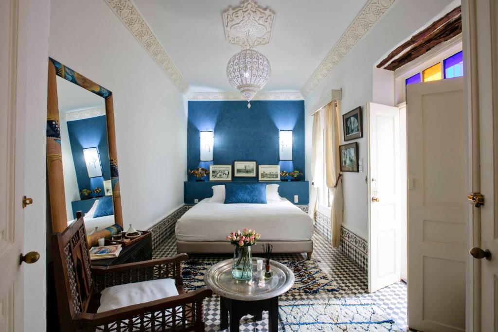 - une chambre avec un lit aux murs bleus et une table dans l'établissement Riad Emotion, à Essaouira