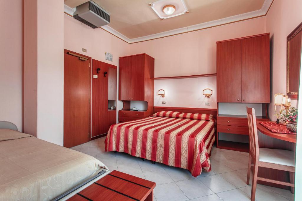 Cette chambre comprend deux lits, un bureau et un lit. dans l'établissement Hotel Villa Pina, à Milano Marittima