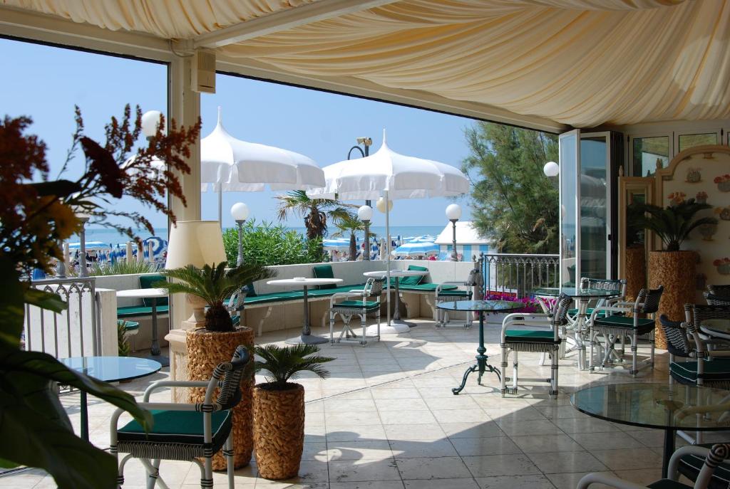 un patio avec tables, chaises et parasols dans l'établissement Hotel Montecarlo, à Lido di Jesolo