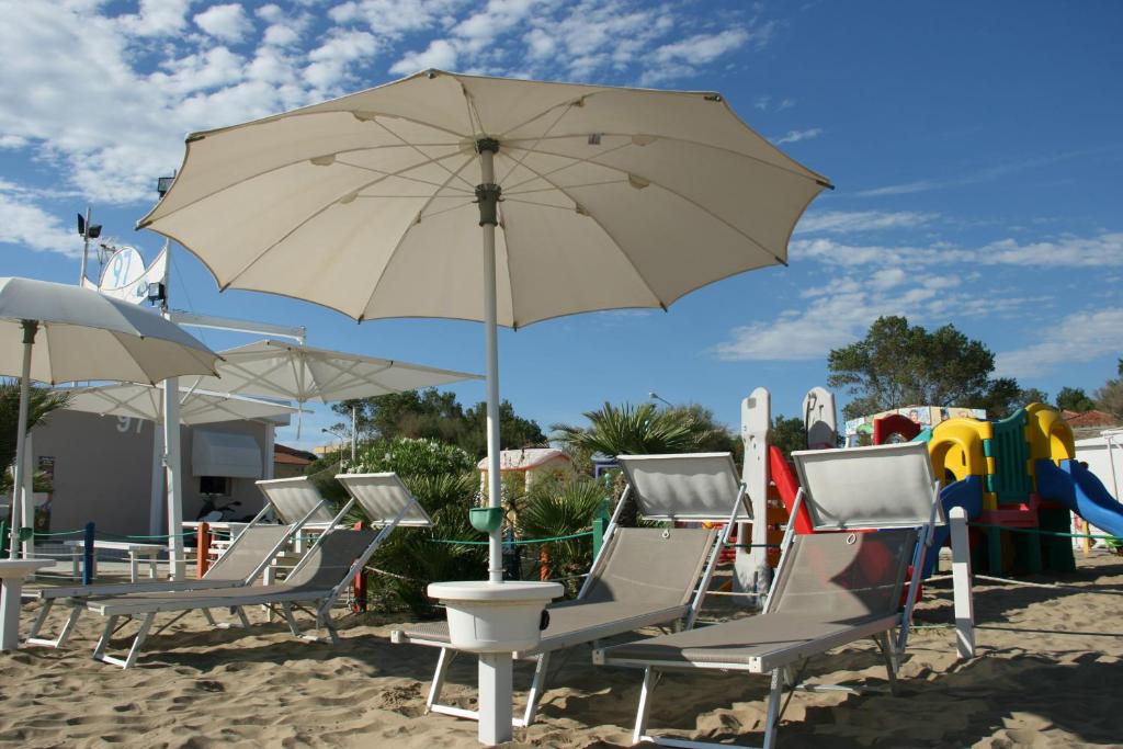 un groupe de chaises et un parasol sur la plage dans l'établissement Hotel Kim, à Rimini