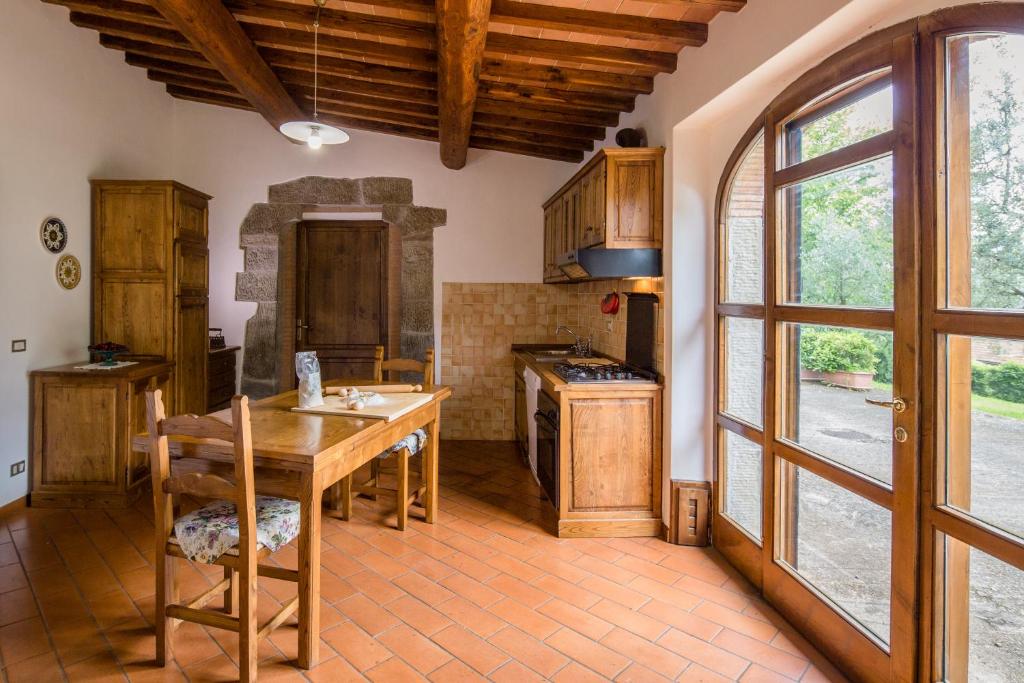 une cuisine avec des armoires en bois et une table en bois dans l'établissement Villa Le Capanne, à Castiglion Fiorentino