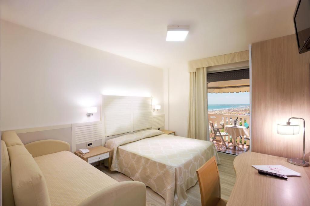 une chambre d'hôtel avec un lit, un canapé et une table dans l'établissement Hotel Savoy, à Caorle