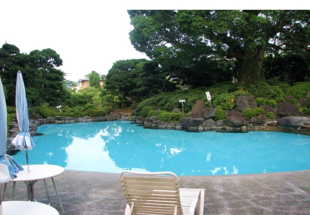 - une grande piscine avec 2 chaises et un parasol dans l'établissement Ohito Hotel, à Izunokuni