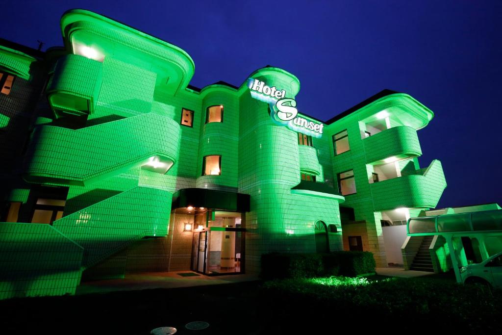 un bâtiment vert avec une enseigne la nuit dans l'établissement Hotel Sunset (Adult Only), à Choshi