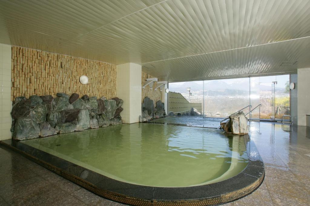 - une grande piscine d'eau dans une chambre avec des rochers dans l'établissement Nunohiki Onsen Komoro, à Komoro