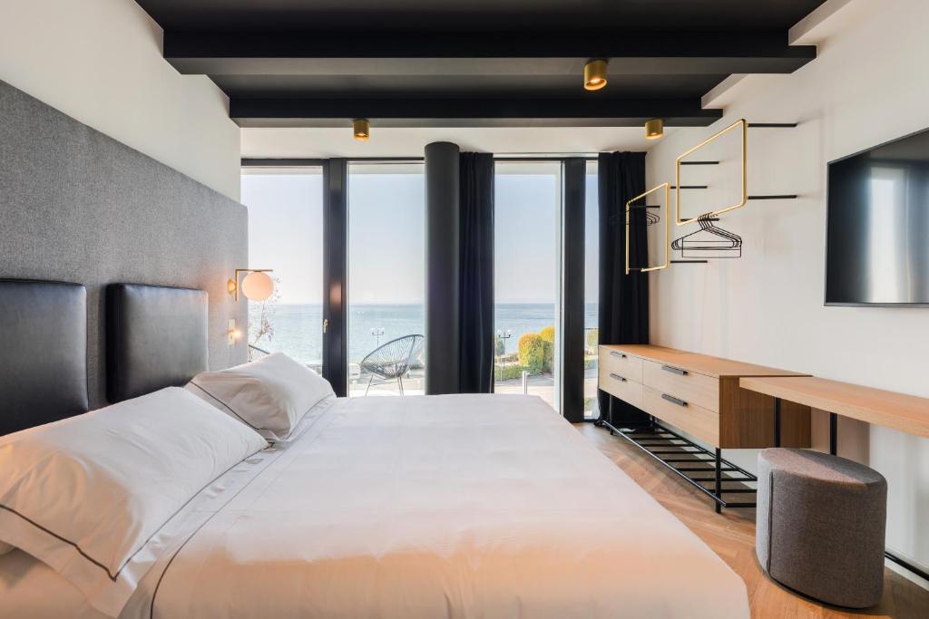 une chambre avec un grand lit et un bureau dans l'établissement MaisonMe Boutique Hotel, à Bardolino