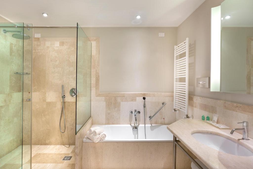 une salle de bain avec une baignoire, un lavabo et une douche dans l'établissement Grande Baia Resort & Spa, à San Teodoro