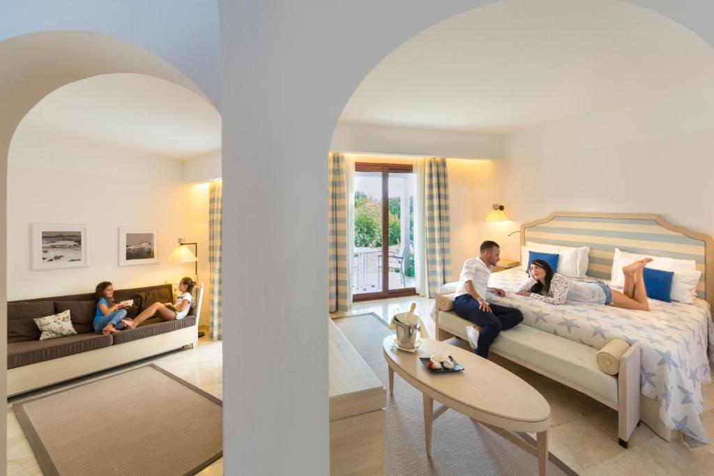 une famille assise sur un lit dans une pièce dans l'établissement Grande Baia Resort & Spa, à San Teodoro 58 autres photos