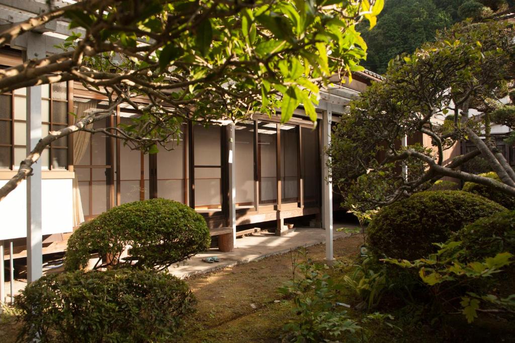 un bâtiment avec des fenêtres et des buissons devant lui dans l'établissement Yuuhiken, à Asago