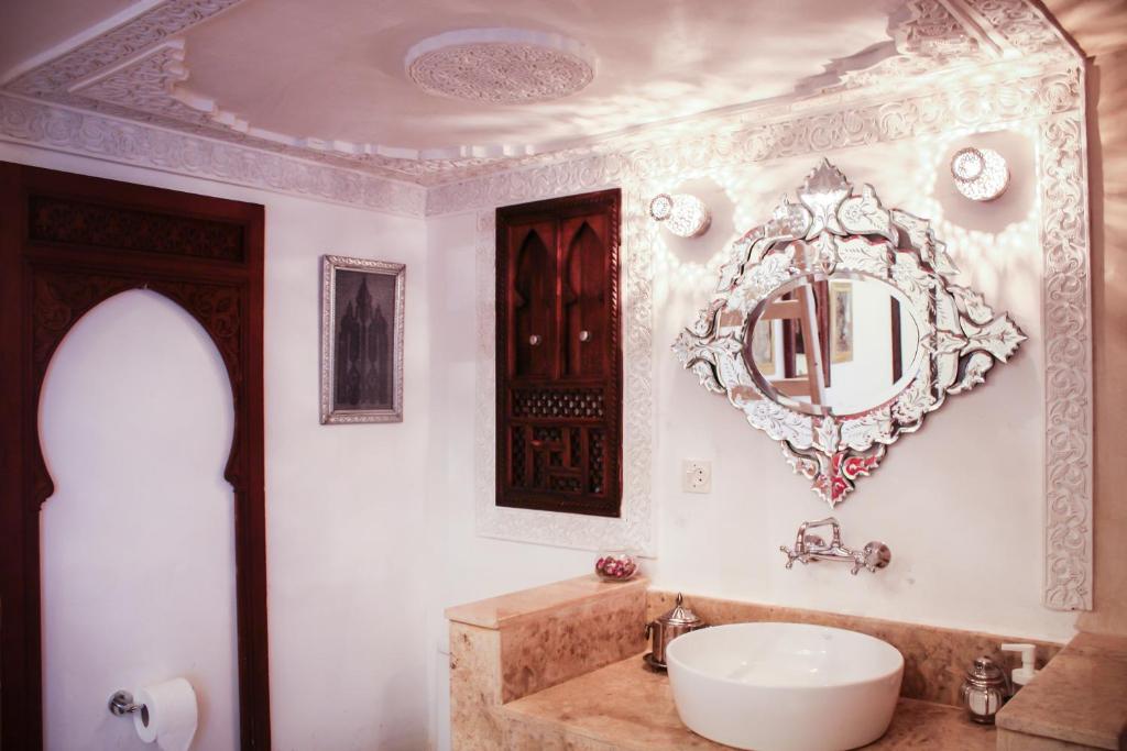 une salle de bain avec un lavabo et un miroir au mur dans l'établissement Riad Dar Arsama, à Fès