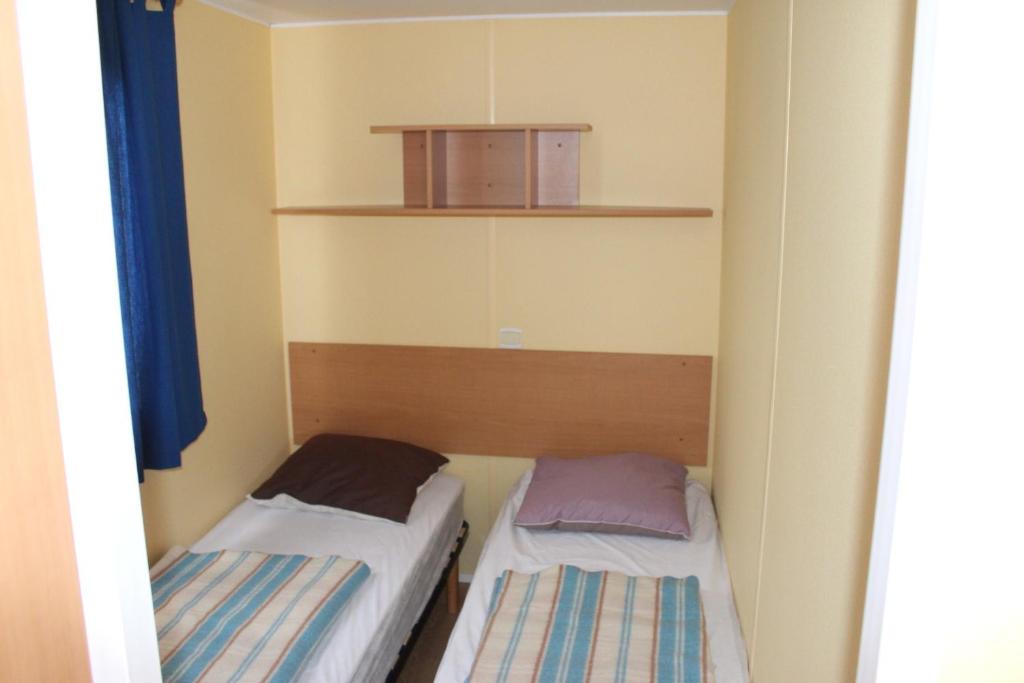 Cette petite chambre comprend deux lits et une boîte. dans l'établissement Camping du Pontis, à Verteillac 37 autres photos