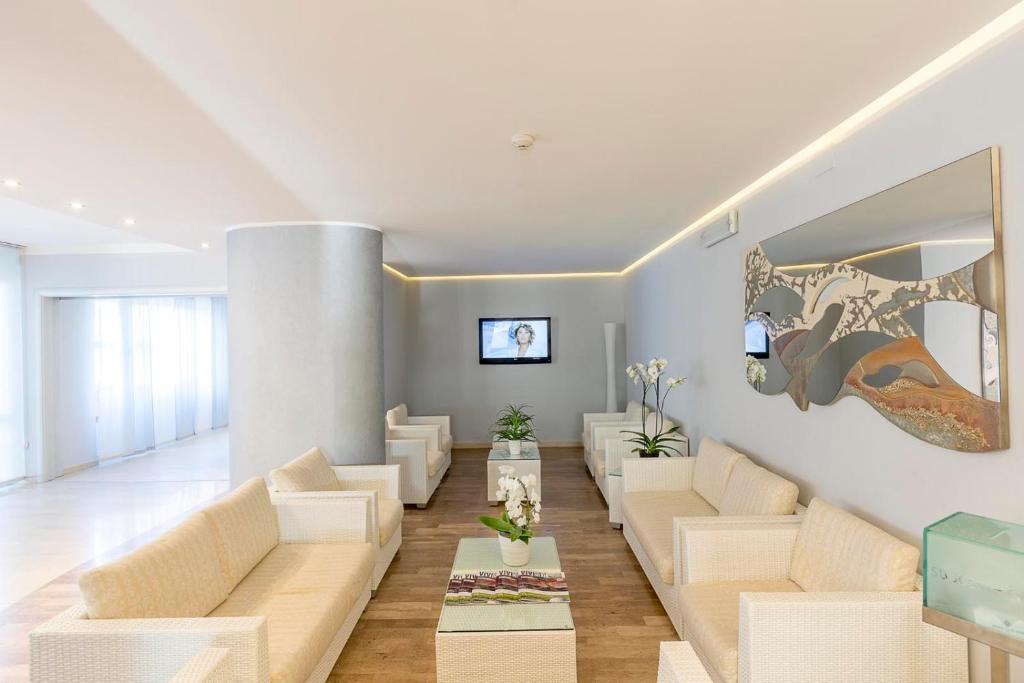 un salon avec des canapés blancs et une table dans l'établissement Hotel Excelsior, à Alba Adriatica