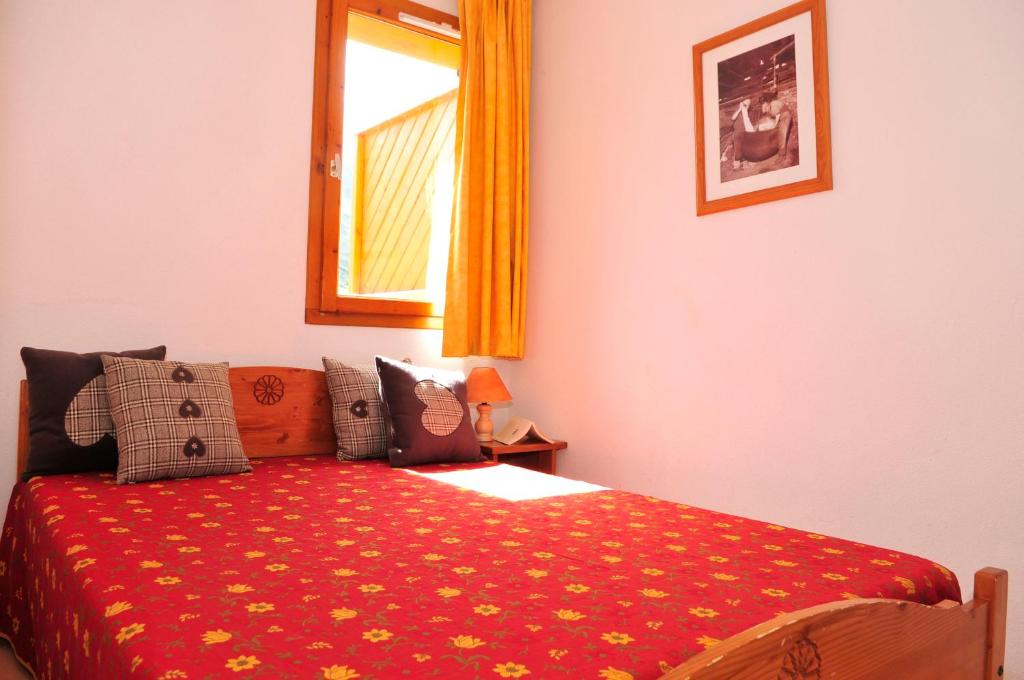 - une chambre avec un lit et une couverture rouge ornée de fleurs jaunes dans l'établissement Résidence Goélia Le Relais des Pistes, à Albiez-le-Vieux
