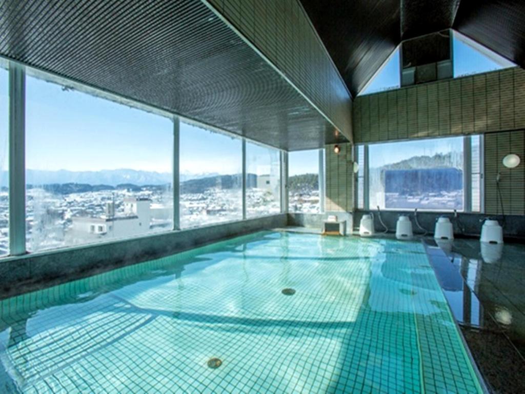une grande piscine dans un immeuble avec des fenêtres dans l'établissement Itoen Hotel Asamanoyu, à Matsumoto