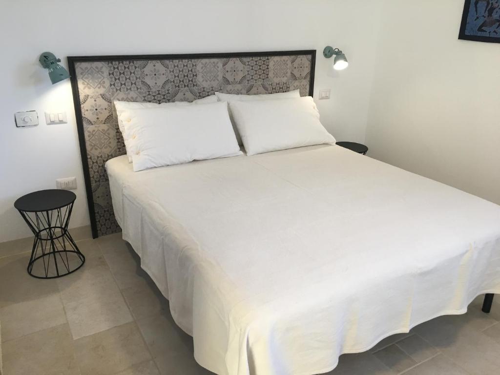 une chambre avec un grand lit avec des draps blancs dans l'établissement Villa Pietraja, à Ugento