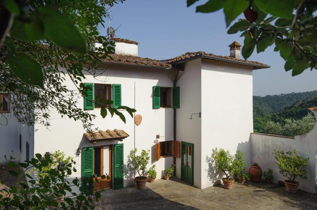 une maison blanche avec des volets verts et des plantes dans l'établissement Chiantivillas Villa Torricella, 27, à Tavarnuzze