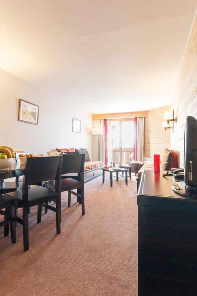 un salon avec une table, des chaises et un canapé dans l'établissement Résidence Pierre & Vacances Le Tikal, à Val Thorens