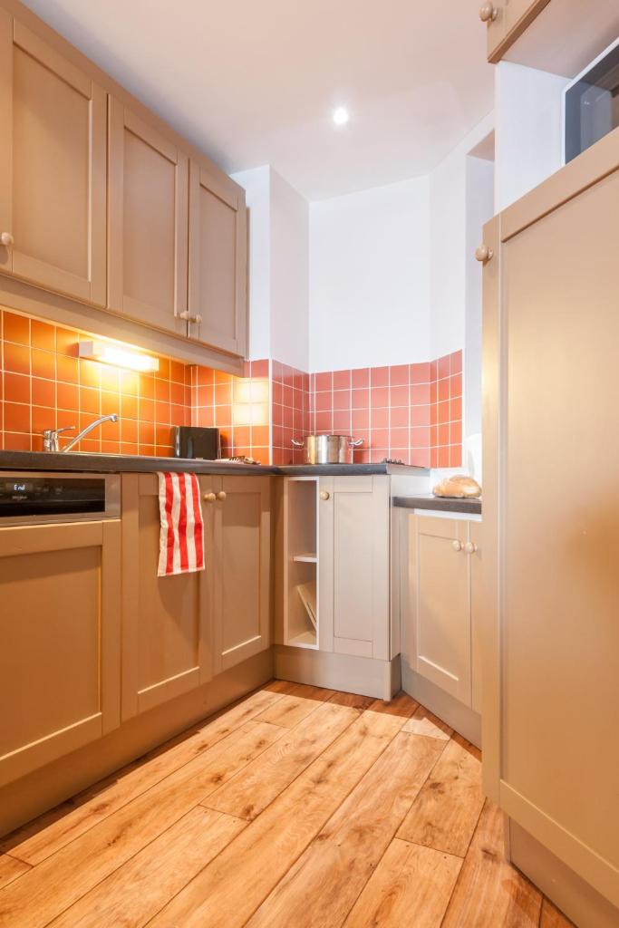 Il comprend une cuisine avec des placards bruns et du parquet. dans l'établissement Résidence Pierre & Vacances Le Tikal, à Val Thorens