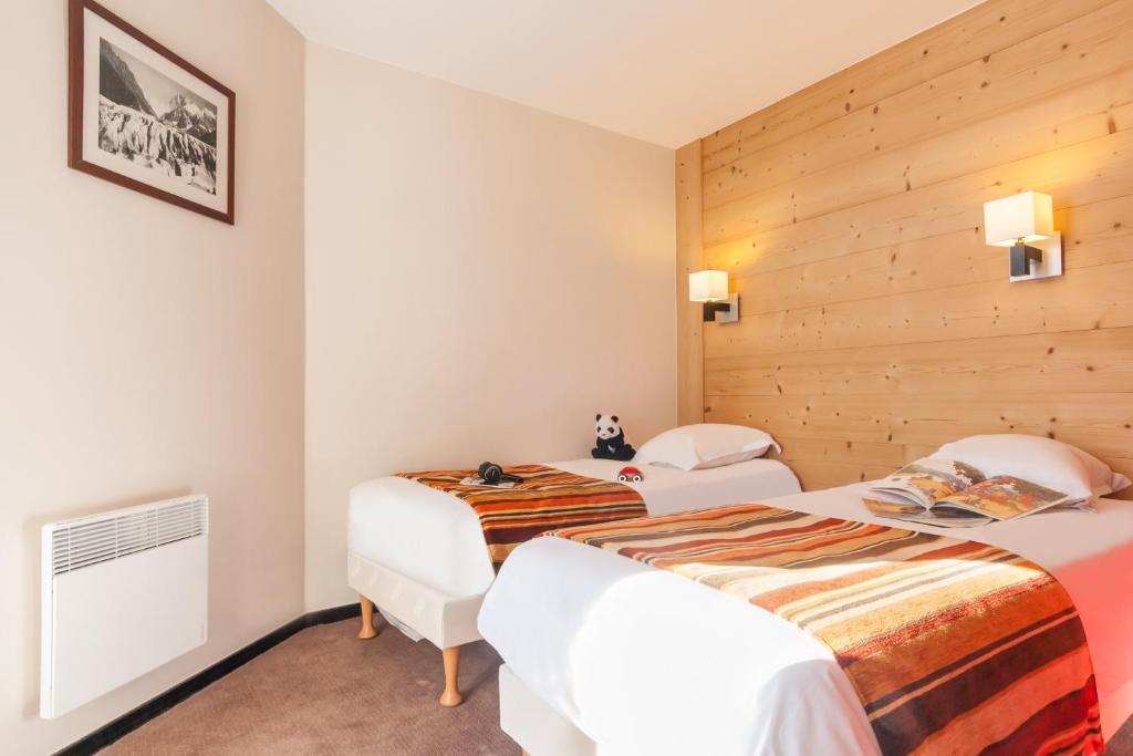 deux lits dans une chambre aux murs en bois dans l'établissement Résidence Pierre & Vacances Le Tikal, à Val Thorens