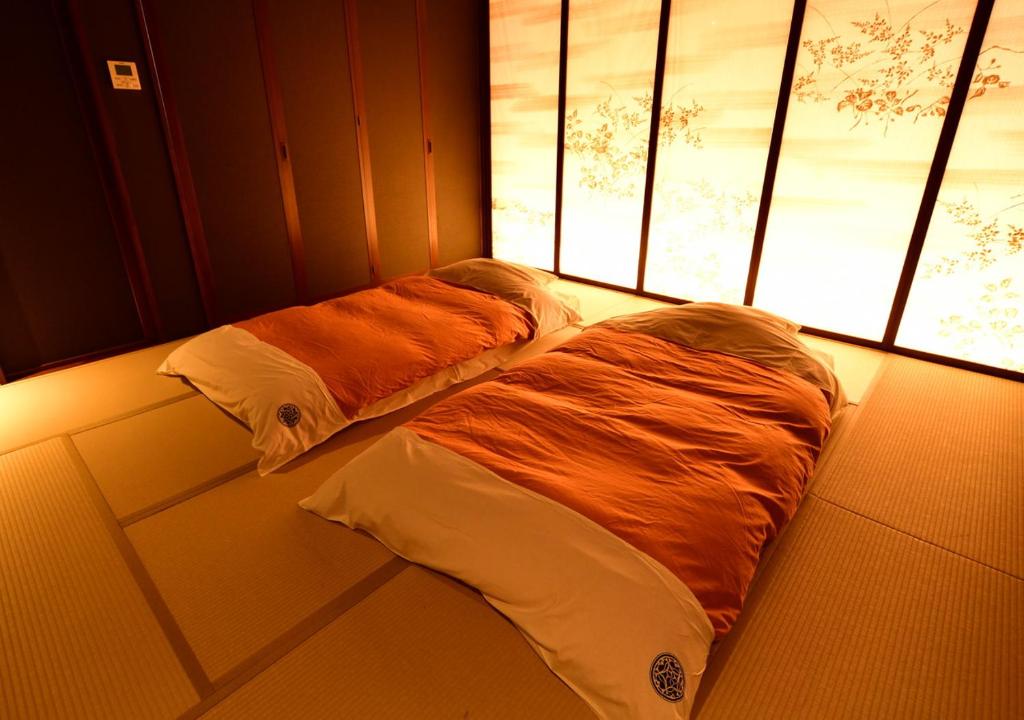 deux lits dans une chambre avec deux fenêtres dans l'établissement Balinese onsen ryokan Hakone Airu, à Hakone 37 autres photos