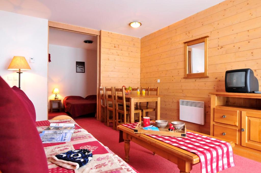 un salon avec une table et une télévision dans l'établissement Résidence Goélia Les Terrasses du Corbier, au Corbier