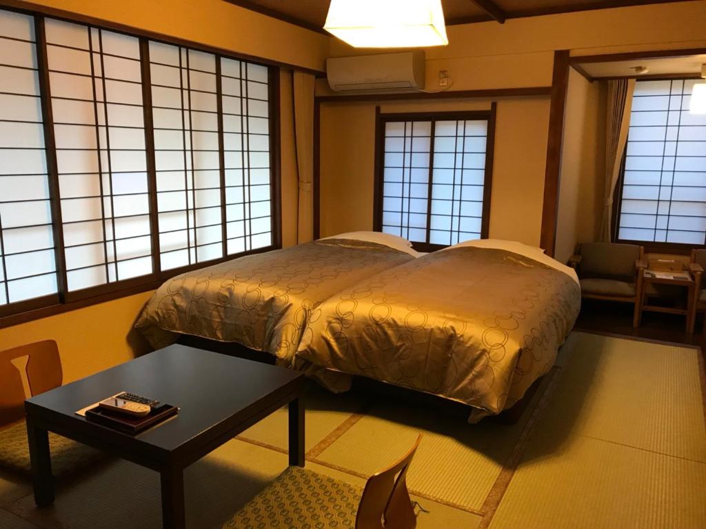 une chambre avec un lit, une table et des fenêtres dans l'établissement Onyado Tsutaya, à Kiso 37 autres photos