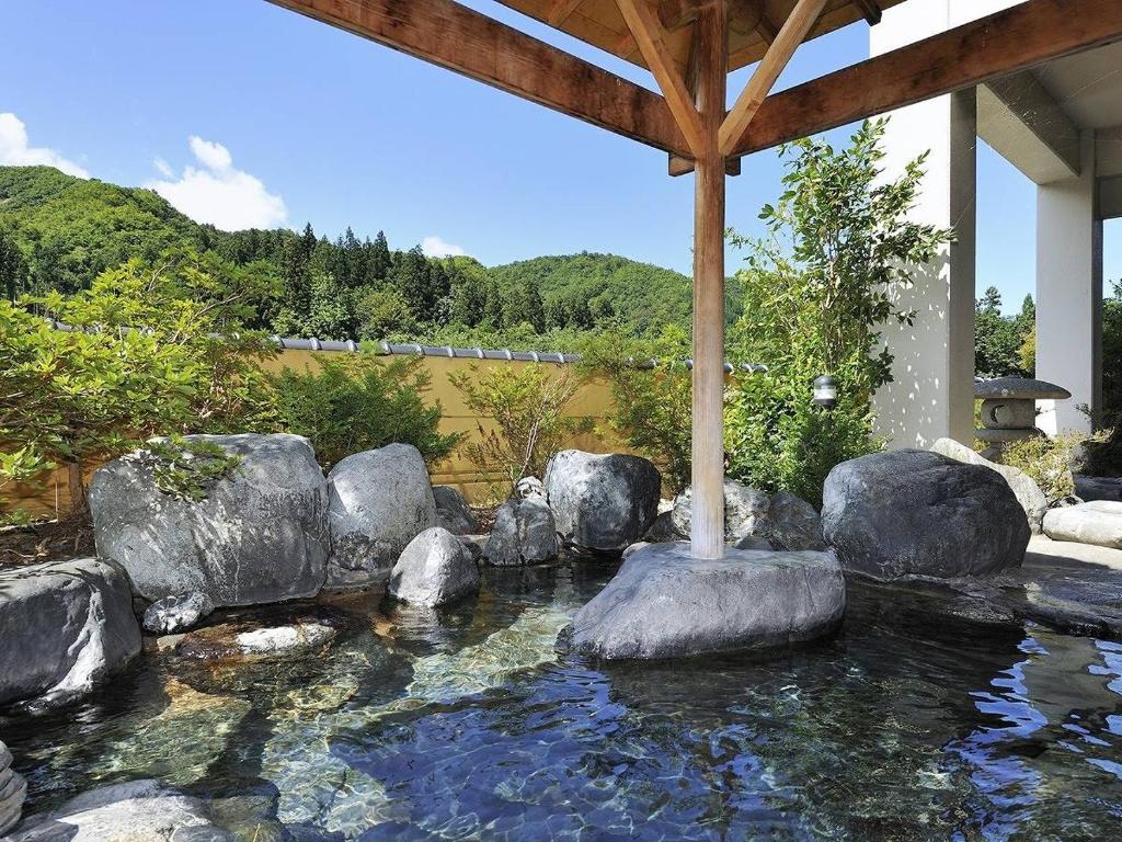 une piscine d'eau avec des rochers dans une maison dans l'établissement Hotel Yumoto, à Utsuno