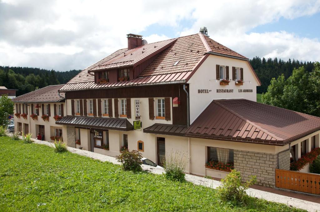 une grande maison avec un toit brun dans l'établissement LOGIS Les Arobiers, à Lamoura