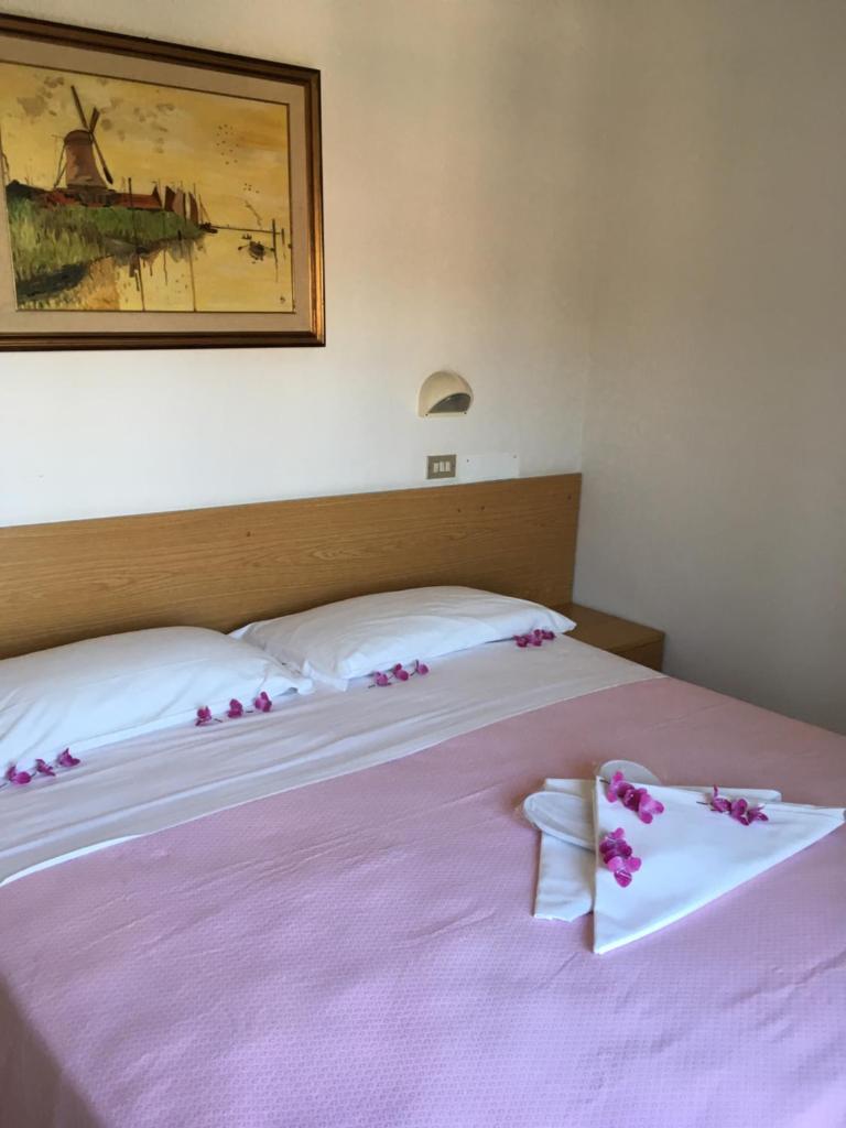 une chambre avec deux lits avec des fleurs roses dessus dans l'établissement Hotel Peonia, à Rimini 26 autres photos