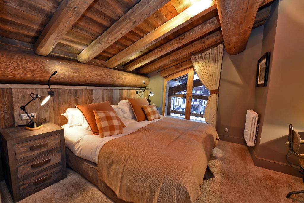 une chambre avec un grand lit dans une pièce avec des plafonds en bois dans l'établissement Maison de Famille Les 5 Frères, à Val dʼIsère