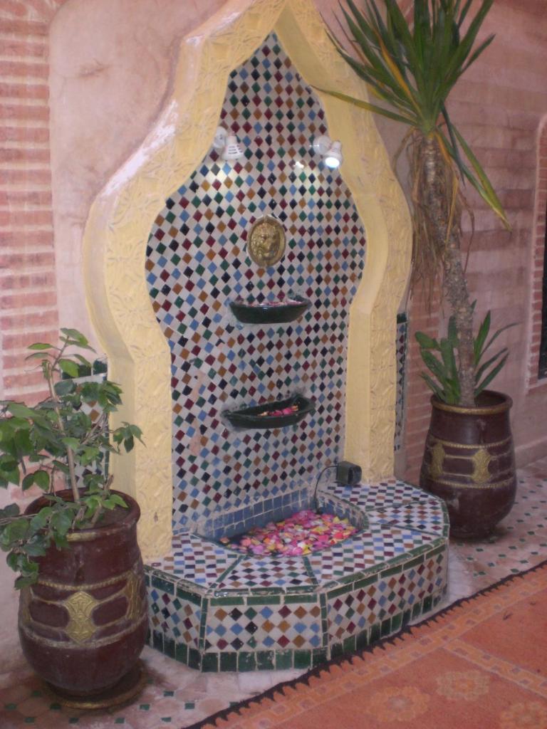 un banc coloré dans une pièce avec deux plantes en pot dans l'établissement Riad Hiba, à Marrakech