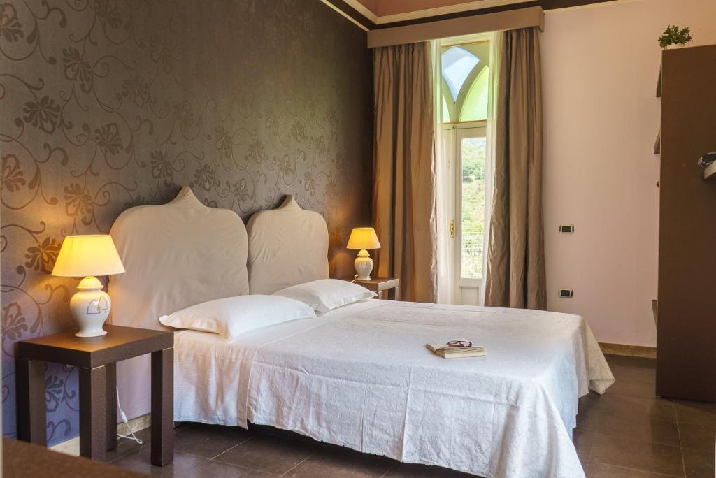 une chambre avec un lit blanc et une fenêtre dans l'établissement Relais La Placa, à Francavilla di Sicilia