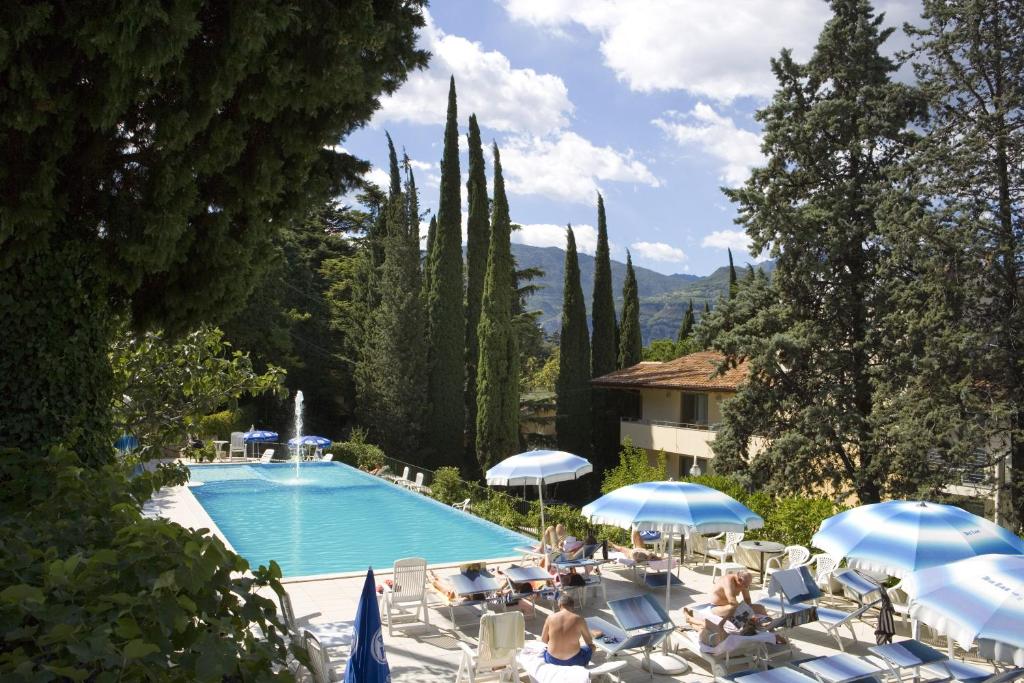 une piscine avec chaises et parasols à côté d'un bâtiment dans l'établissement Beach Hotel Du Lac Malcesine, à Malcesine