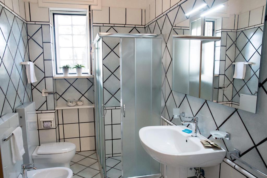 une salle de bain avec un lavabo, des toilettes et un miroir dans l'établissement Villa Conca D'oro, à Gallipoli