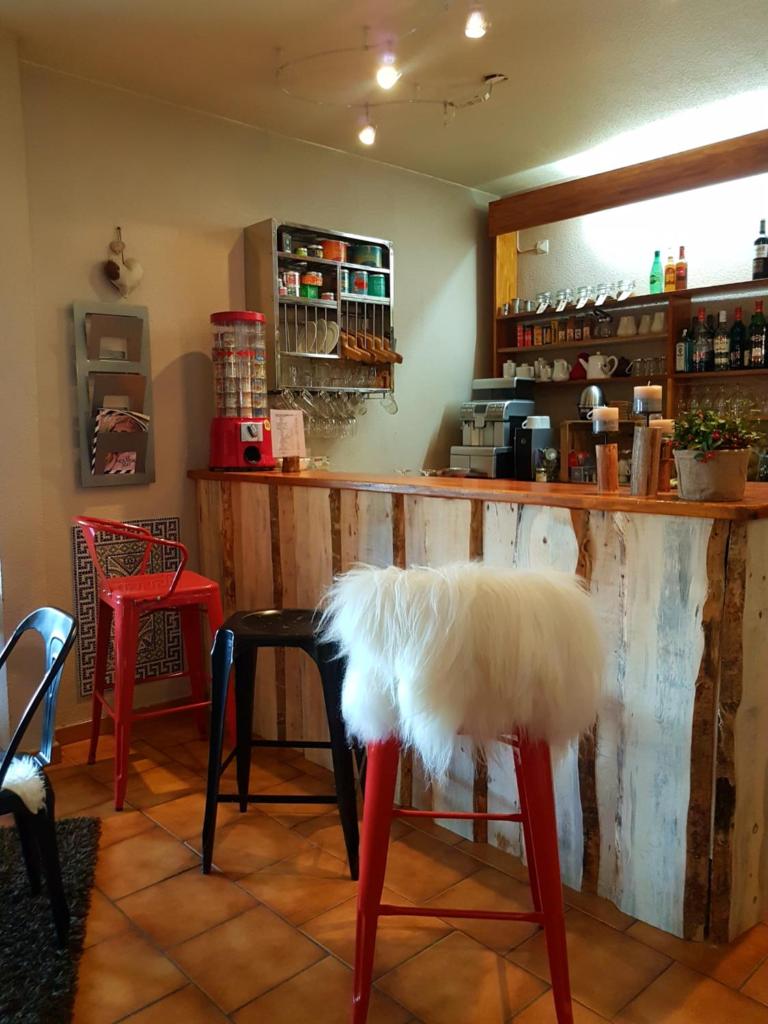 - un bar avec des tabourets rouges et blancs dans la chambre dans l'établissement Hôtel Yaka, aux Angles