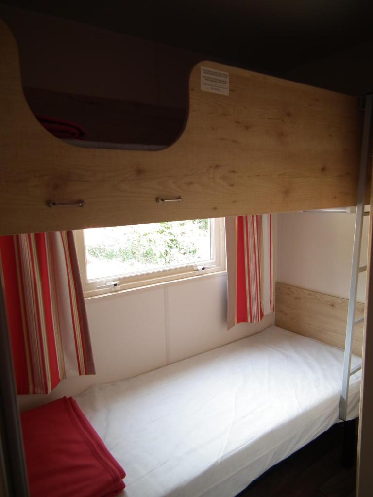 Ce lit superposé se trouve dans un dortoir doté d'une fenêtre. dans l'établissement Camping La Pindière, à Héric